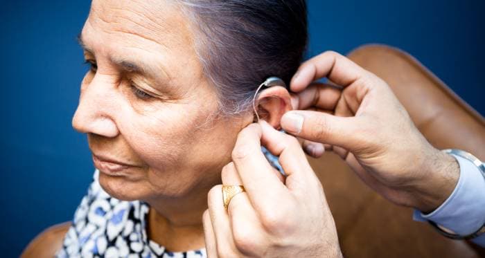 An elderly woman is being fitted with a hearing aid by an Audiologist.